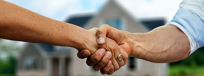 Personas dándose la mano frente al inmueble