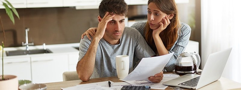 Pareja mirando preocupados facturas de deudas sin prescribir
