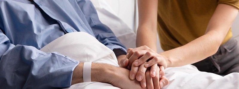 Mujer le da mano a su marido en hospital