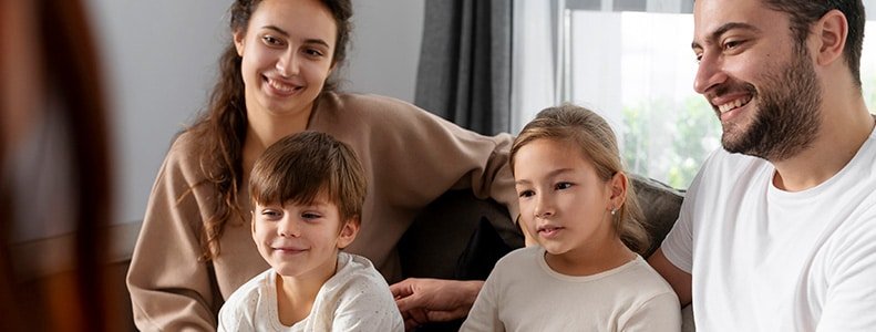 Padres con sus dos hijos sentados en el sillon de la sala