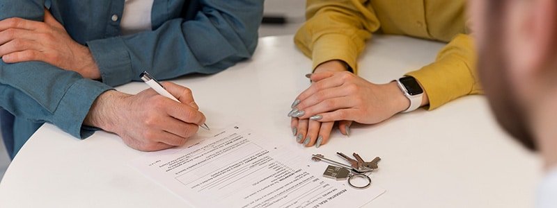 Arrendador, inquilinos y agente de la inmobiliaria firmando contrato de alquiler